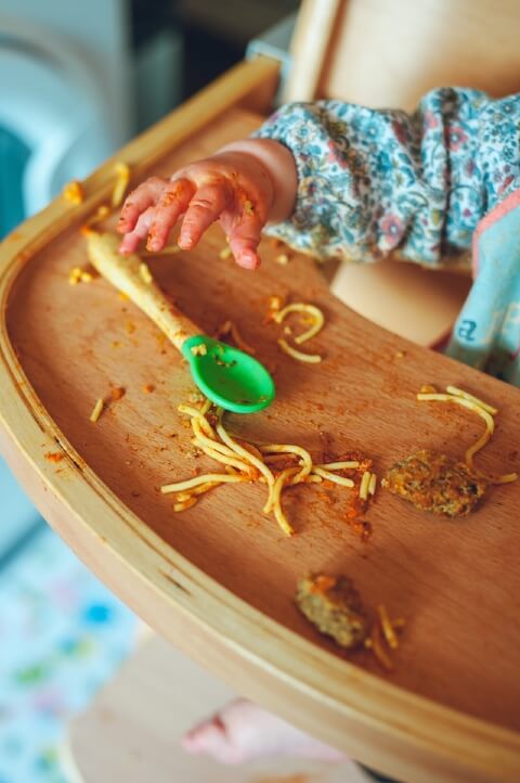 Toddler eating at high chair making a mess