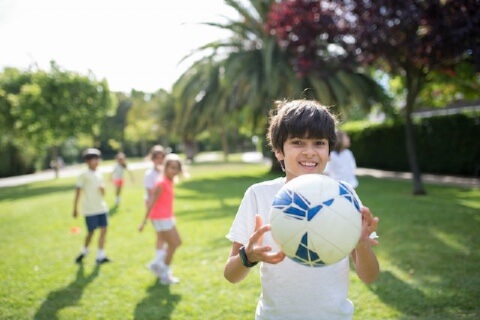 a boy playing football outside with his friends