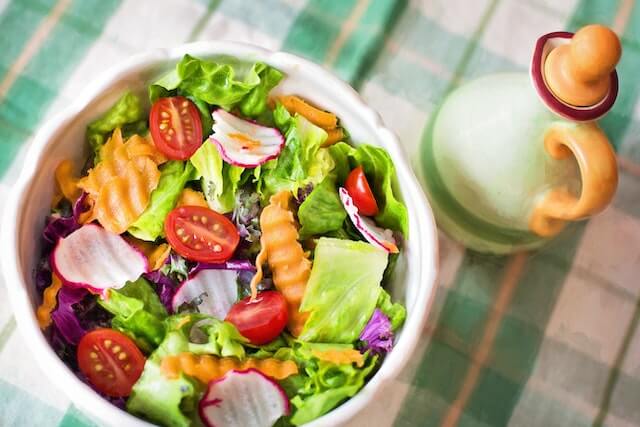 A bowl of salad with olive oil expressing the health benefits of the Mediterranean diet