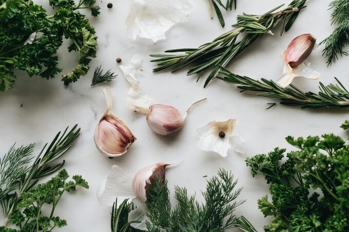 various herbs and cloves of garlic on a granite worktop