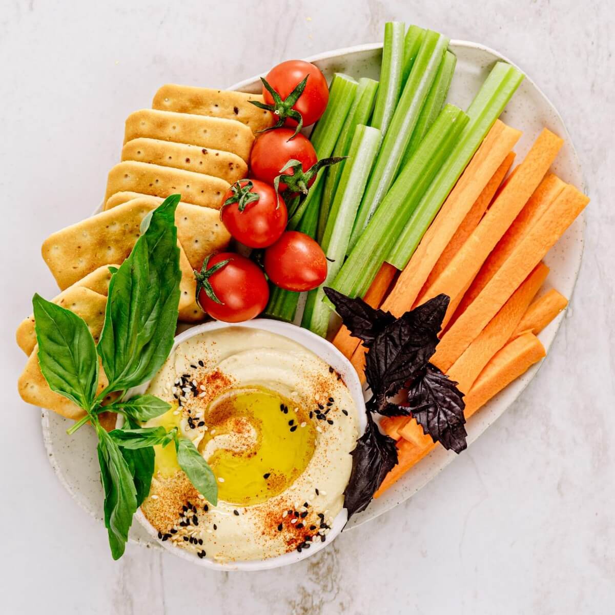 healthy foods including crudités and hummus on a plate